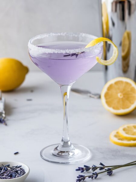 A beautifully crafted Lavender Lemon Drop Martini in a chilled glass, rimmed with sugar and garnished with a lemon twist and edible lavender flowers.