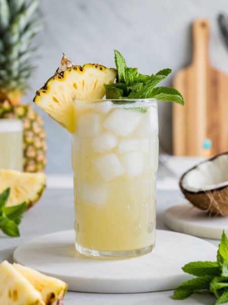 A refreshing Coconut Water Pineapple Cooler served in a tall glass with ice, garnished with a pineapple wedge and mint, perfect for hot summer days.