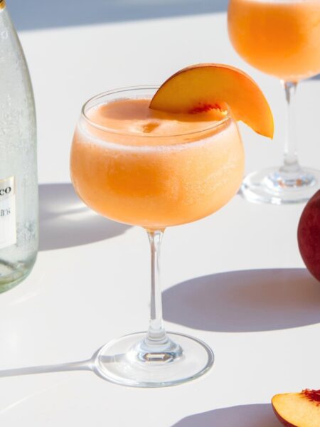 Refreshing frozen peach bellini cocktail with fresh peach slices