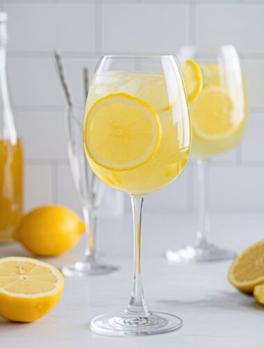 A bright and bubbly Limoncello Spritz served in a wine glass with fresh lemon slices and ice, set against a sunny, inviting background.